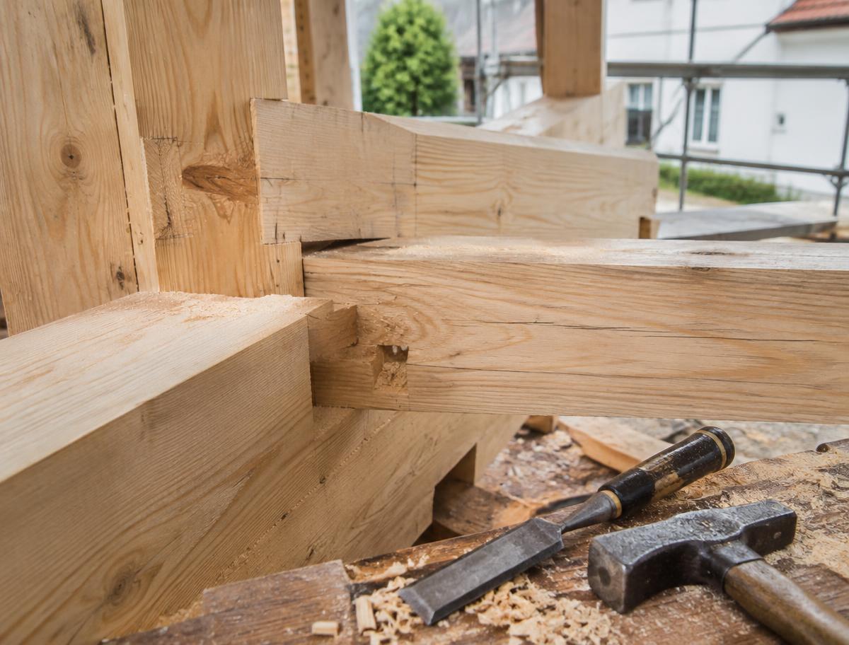 Houten balken met pen-en-gatverbinding, met beitel en hamer op de werkbank